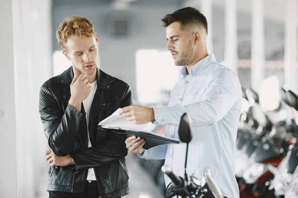 Two adults discussing purchasing options at a motorcycle dealership.